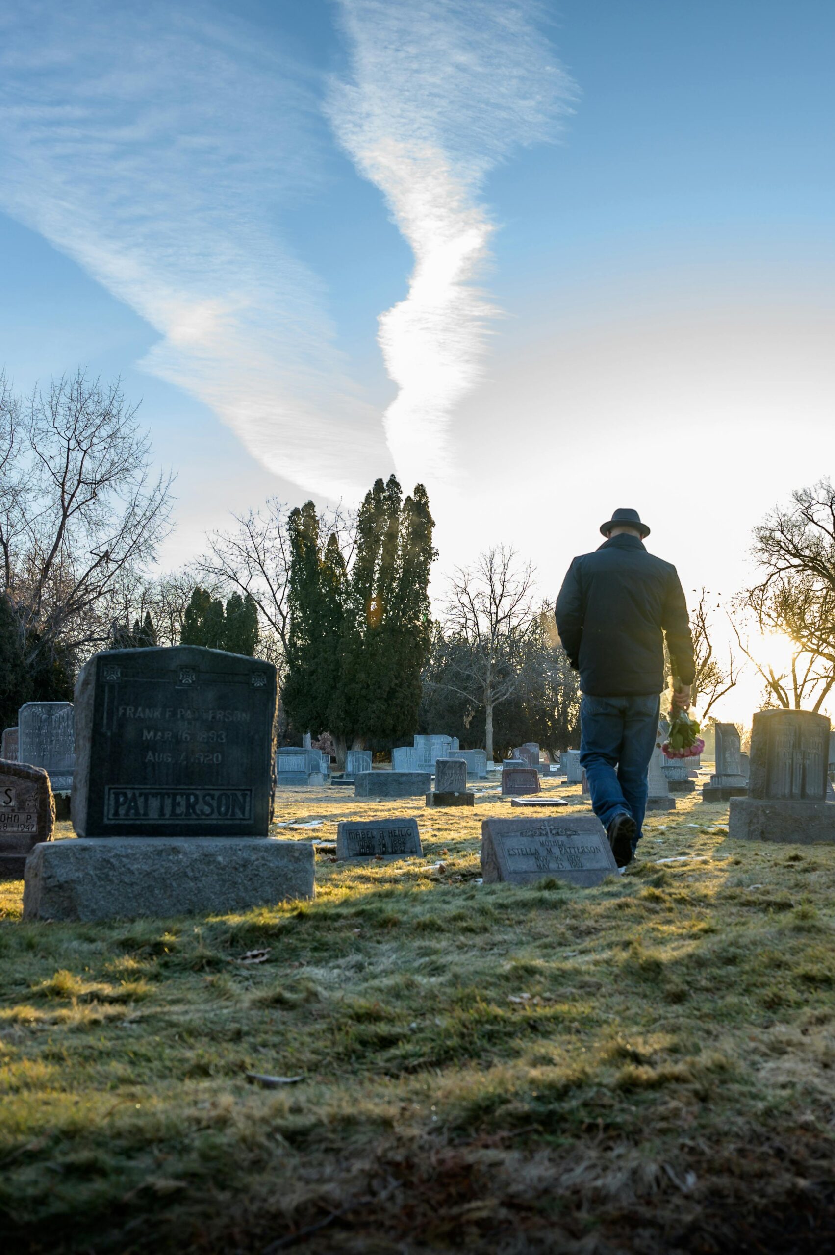 pexels-photo-3608427-3608427 A man walks through a tranquil graveyard at dawn, surrounded by gravestones and trees.